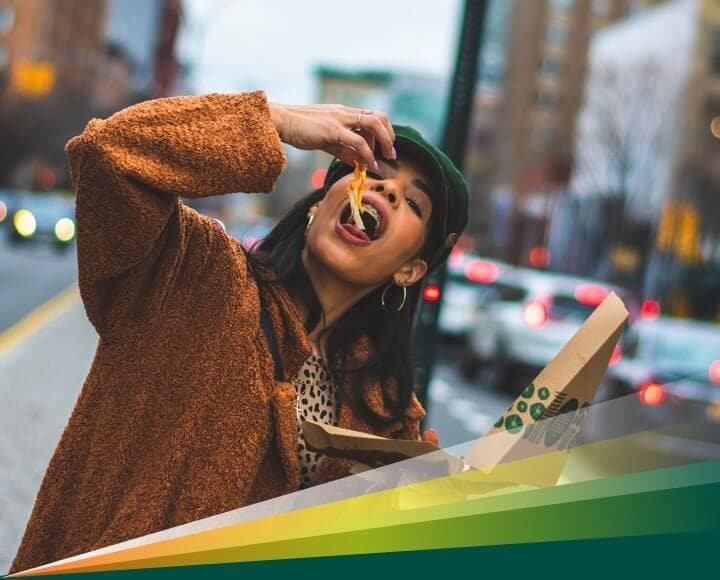 Woman eating pizza on a city street